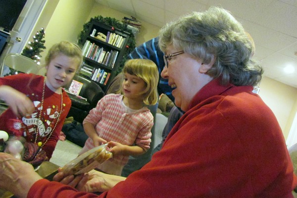 Elsie is helped by two grandchildren to open her gift