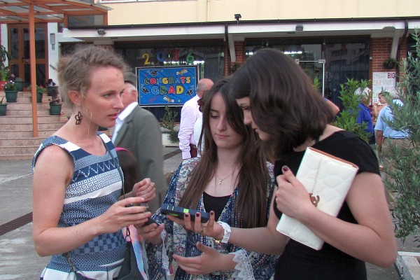 Katrina, Romina,, and Irena gather around an image on a phone