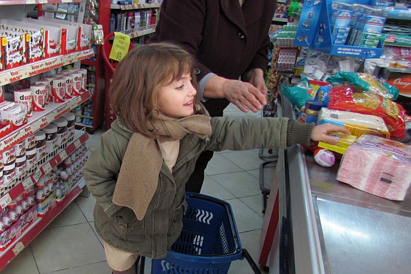 a young girl helps her mother with groceries