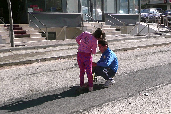 a brother helps his sister with her scooter