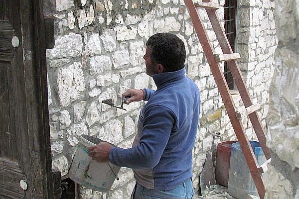 mason fixing a stone wall inside a house in tside the castle