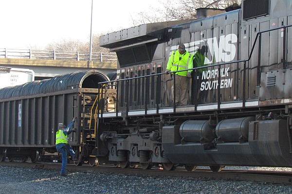 Close-up of men working with NS 9084 locomotive to make a train
