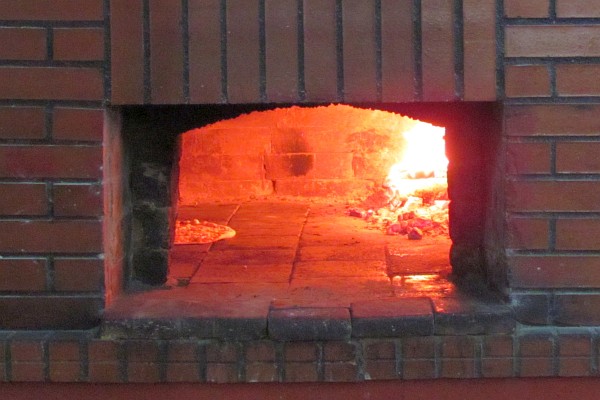 wood-fired oven cooks a pizza