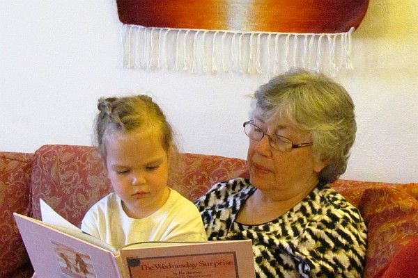 Sydney listens and watches Elsie read to her