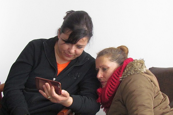 two mothers sharing a moment with a cell phone