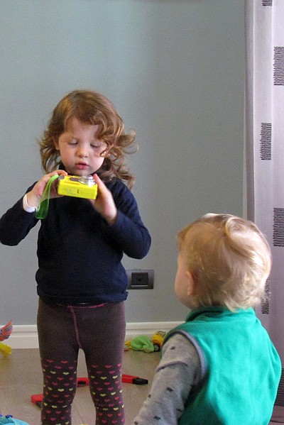 Emily plays with a toy camera whhile Joseph watches