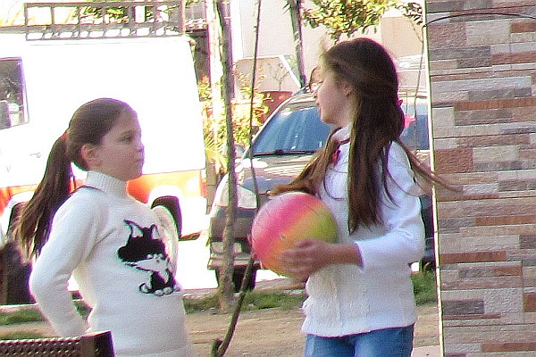 two young gisls playing in the park outside of our apartment building 