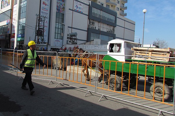 a road worker in safety colored vest is passed by a horse drawn wagon