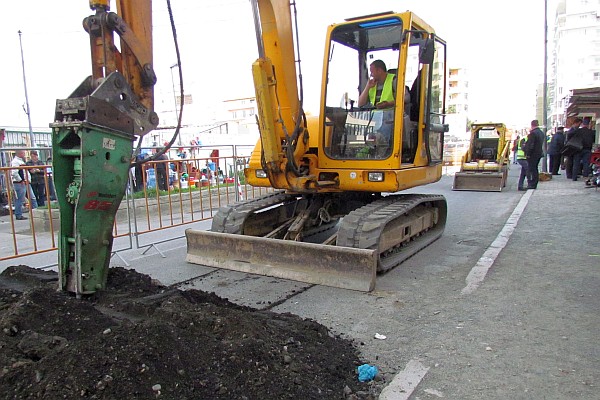 an excavator is breaking up the road above the water pipes