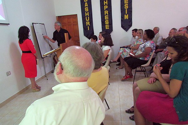 Leon makes a point in his sermon with Klementina interpreting