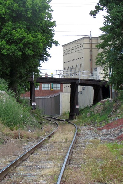 train tracks bend under a wooden bridge