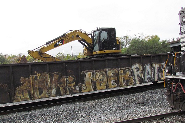 back-hoe on gondola car with grafitti